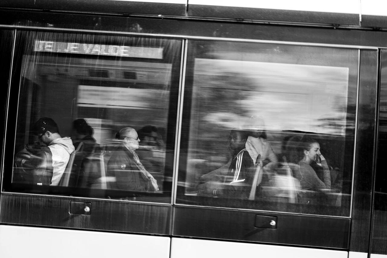 Des personnes acssise dans le tram de Brest. La  photo est prise à travars la vitre avec des reflets