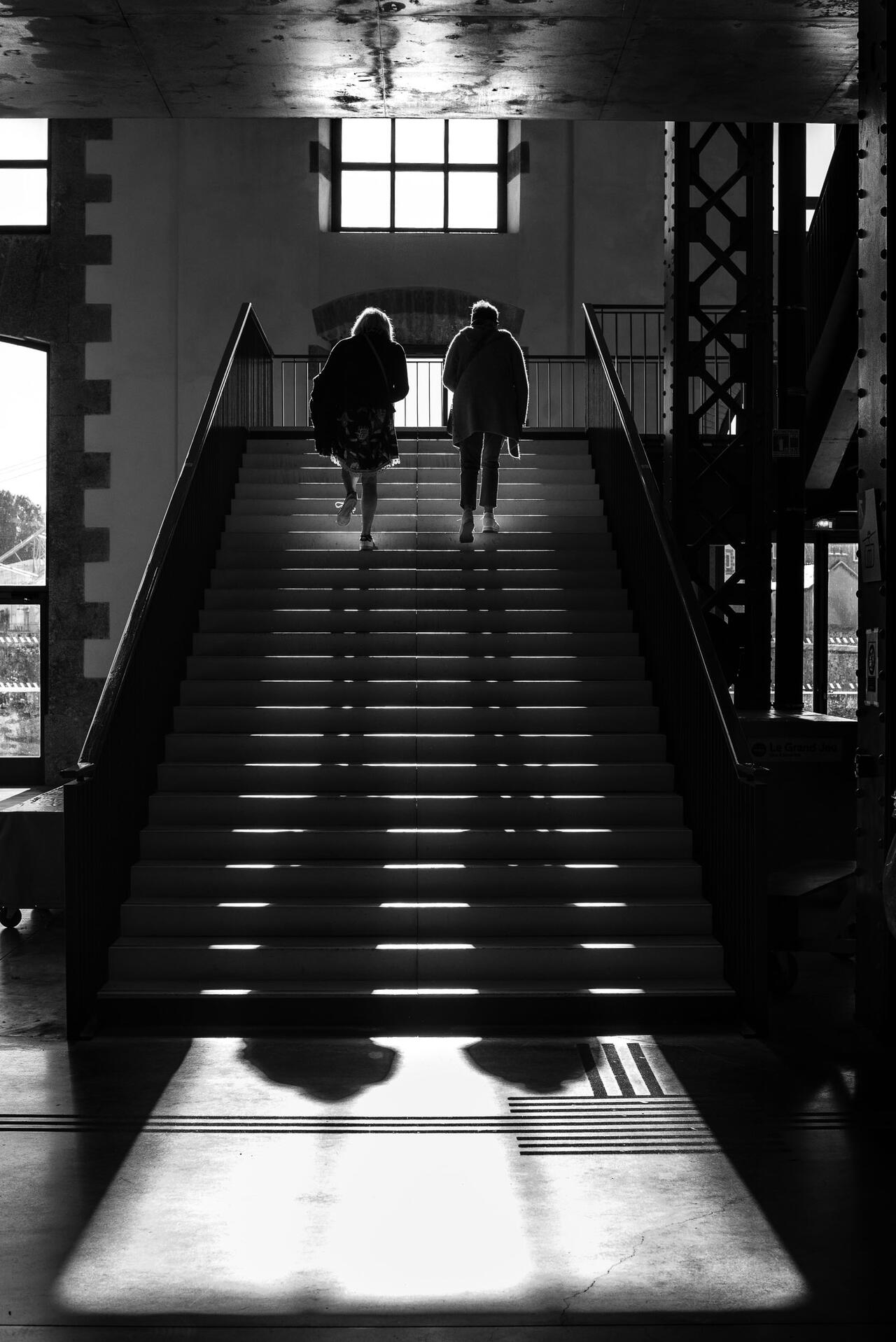 Des personnes montent des escaleir à Brest. Leurs ombres soint projetées sur les marches