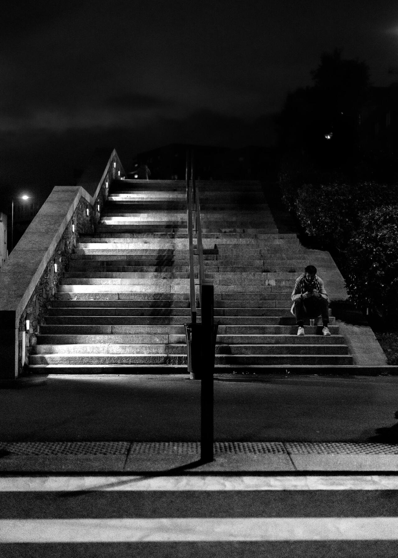 Un homm est assis en bas d'escalier la nuit