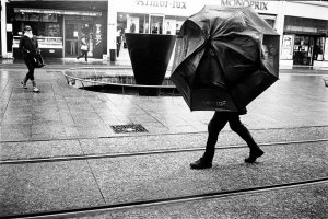 Un homme marche rue de Siam avec un parapluie