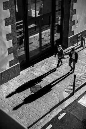 Un couple marche devant les Capucins à Brest. Leur ombre est projetée sur le trotoir
