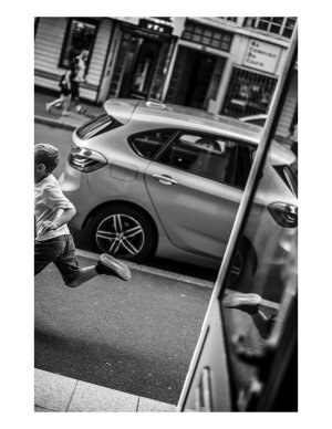Un garçon cour, on voit son dos et sa jambe. son pied se reflete dans un panneau
